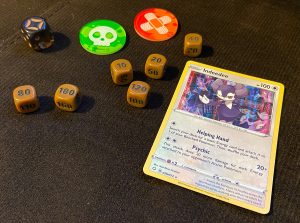 Some small damage counter dice with multiples of 10 on them, a poison and burn marker, a standard six-sided die and an Indeedee card for reference