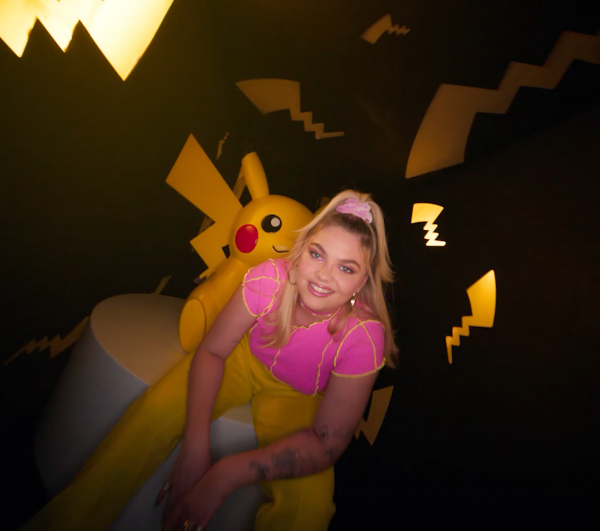 Picture of Louane looking at the camera with a Pikachu behind her